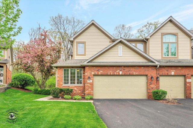townhome / multi-family property featuring roof with shingles, a front yard, driveway, and brick siding