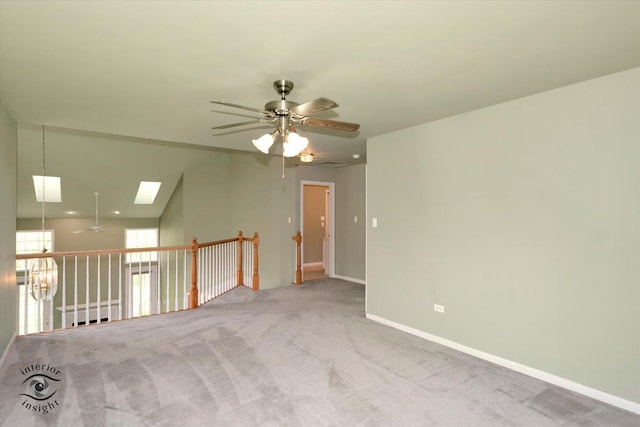 interior space featuring a skylight, baseboards, ceiling fan, and carpet