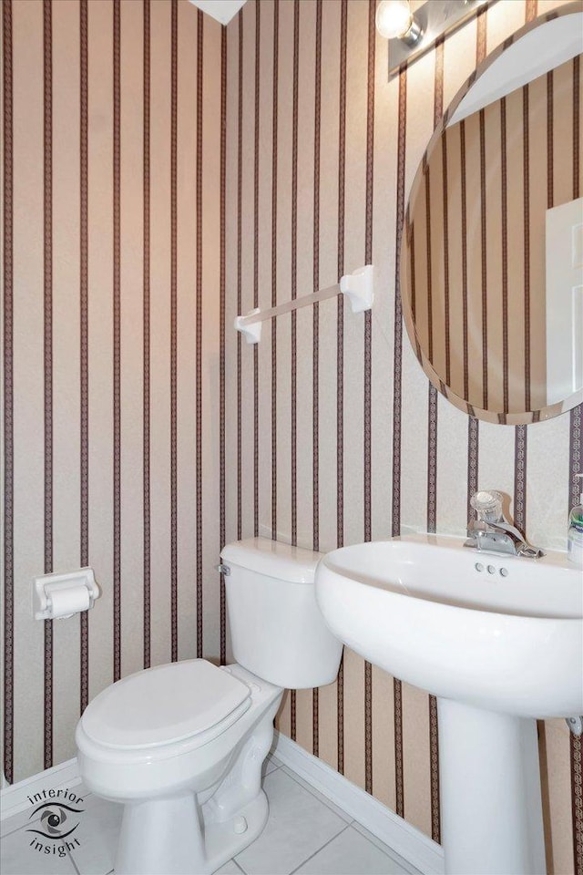 bathroom featuring toilet, wallpapered walls, baseboards, and tile patterned flooring