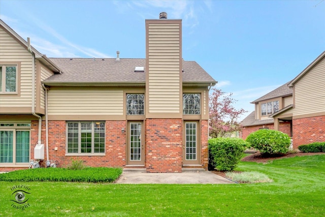rear view of house with a lawn, brick siding, and a patio