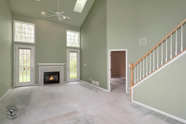 unfurnished living room with ceiling fan, high vaulted ceiling, visible vents, and baseboards