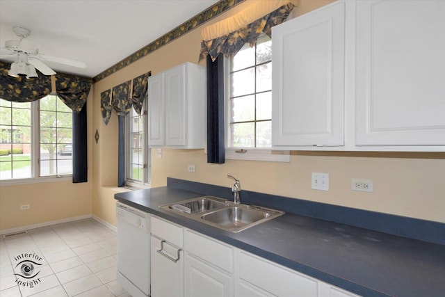 kitchen featuring a ceiling fan, white dishwasher, dark countertops, a sink, and white cabinetry