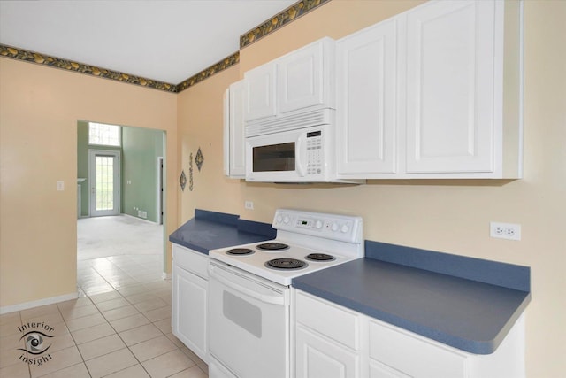 kitchen featuring dark countertops, white cabinetry, light tile patterned flooring, and white appliances