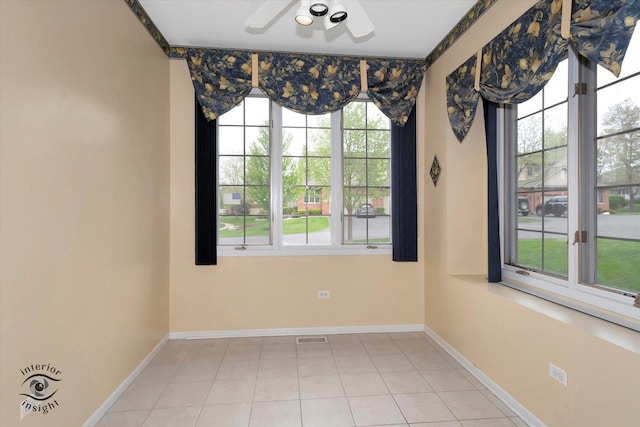 spare room featuring baseboards, ceiling fan, visible vents, and light tile patterned floors