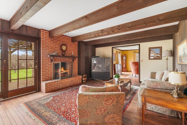living room with beam ceiling, hardwood / wood-style flooring, and a fireplace