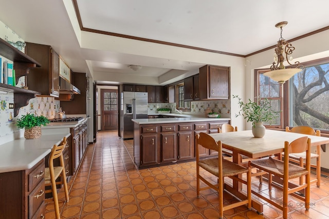 kitchen featuring light countertops, decorative backsplash, dark brown cabinetry, and stainless steel fridge