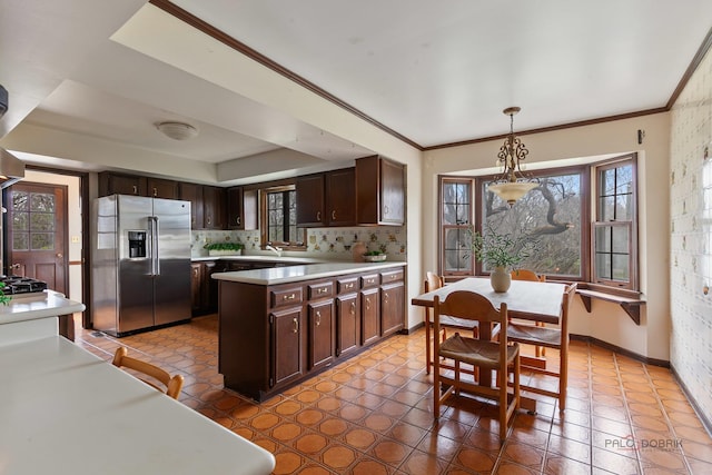 kitchen featuring light countertops, a peninsula, dark brown cabinetry, and stainless steel fridge with ice dispenser