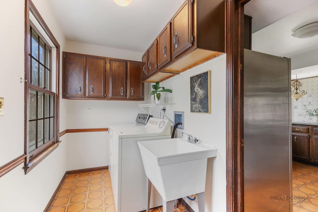 clothes washing area with independent washer and dryer, cabinet space, a sink, baseboards, and light floors
