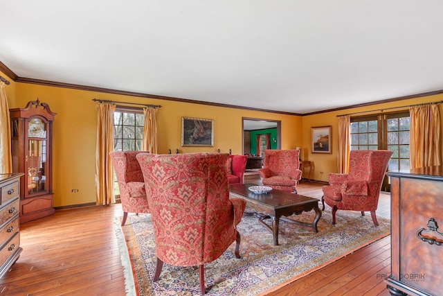 living room with crown molding, baseboards, and light wood-style flooring