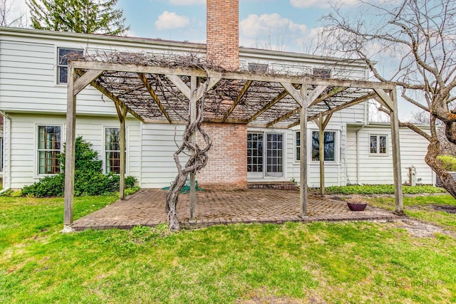 rear view of property featuring a yard, a pergola, a chimney, and a patio