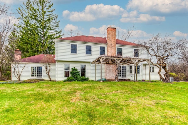 back of house with a yard, a pergola, and a chimney