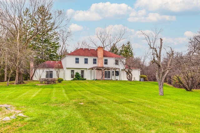 back of property with a chimney and a yard