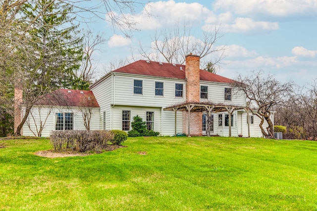 rear view of house featuring a yard, a pergola, and a chimney