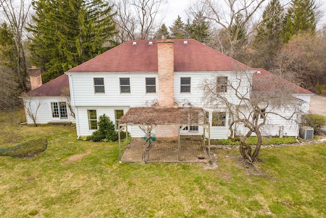 back of house with a lawn, central air condition unit, and a chimney