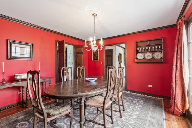 dining space with baseboards, a chandelier, ornamental molding, and wood finished floors