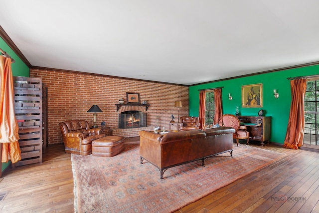 living room featuring wood-type flooring, brick wall, ornamental molding, and a fireplace