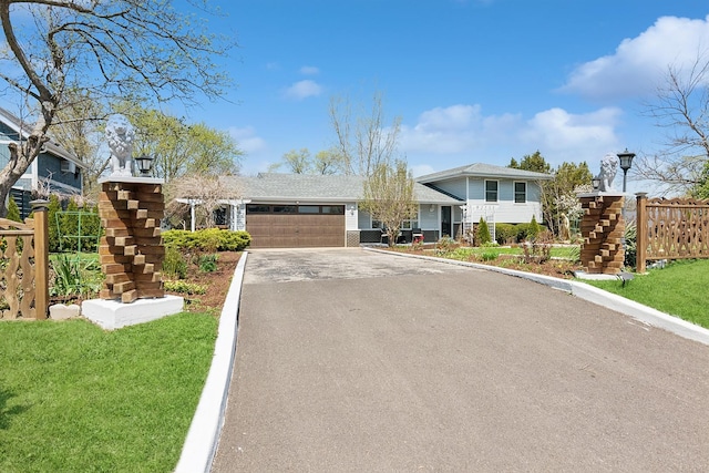 tri-level home with a garage, fence, a front lawn, and aphalt driveway