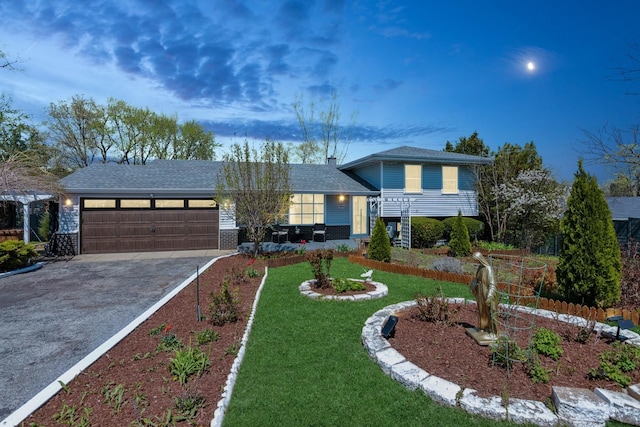 split level home featuring a garage, a shingled roof, concrete driveway, and a front yard