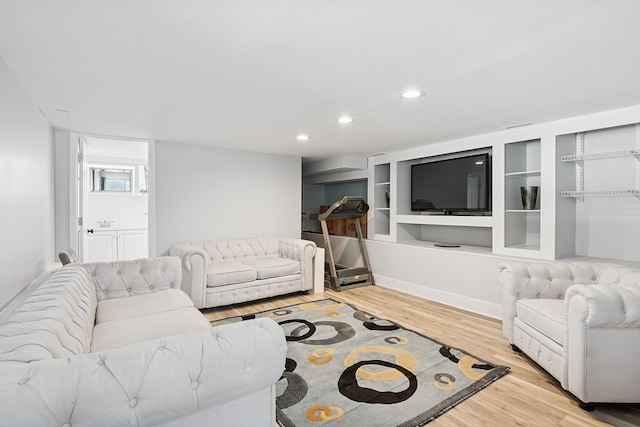 living area featuring built in shelves, recessed lighting, and wood finished floors