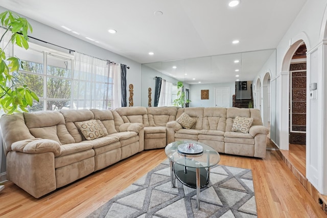 living area with arched walkways, recessed lighting, and light wood-type flooring