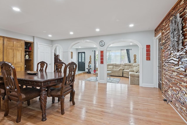dining room featuring light wood-style floors, arched walkways, baseboards, and recessed lighting