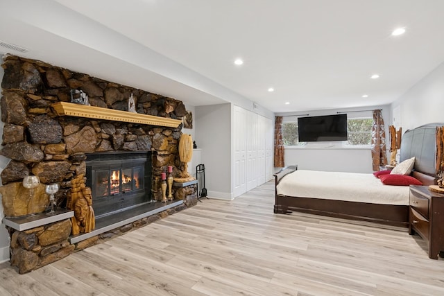 bedroom with light wood finished floors, a stone fireplace, recessed lighting, baseboards, and visible vents