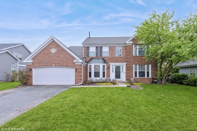 colonial inspired home featuring a garage, driveway, a front lawn, and brick siding
