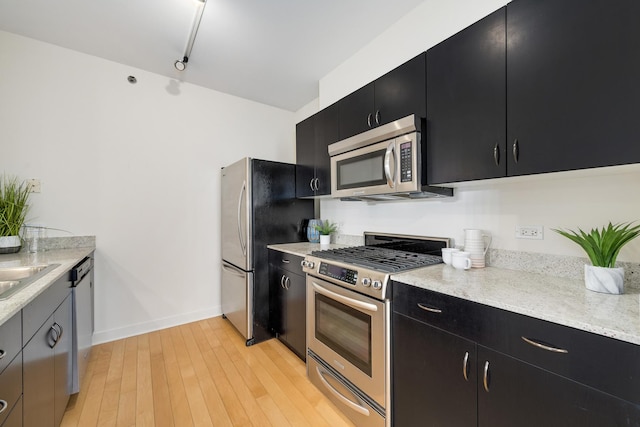 8 E Randolph St Unit 3002, Chicago, IL 60601 - kitchen with baseboards, dark cabinets, a sink, light wood finished floors, and stainless steel appliances
