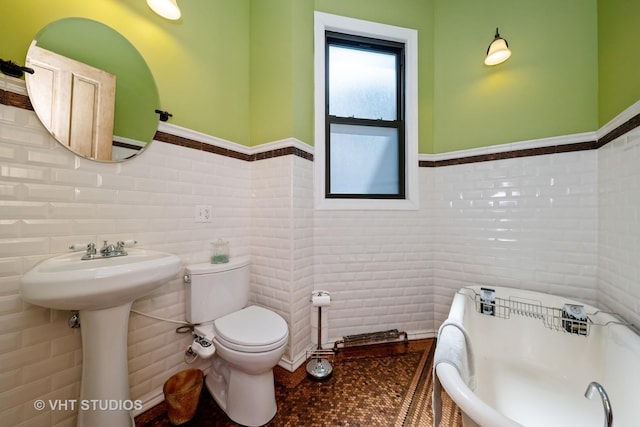 3912 S Prairie Ave, Chicago, IL 60653 - bathroom with tile walls, a wainscoted wall, and a freestanding tub