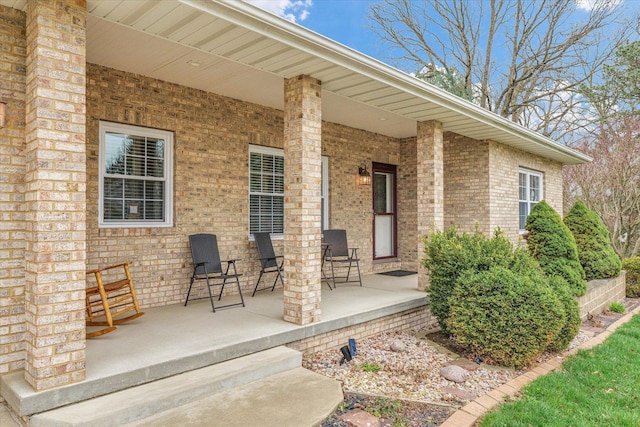 entrance to property featuring covered porch and brick siding
