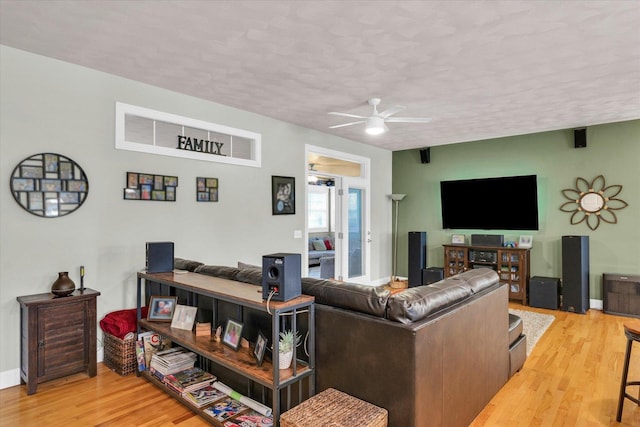 living area with a textured ceiling, ceiling fan, baseboards, and wood finished floors