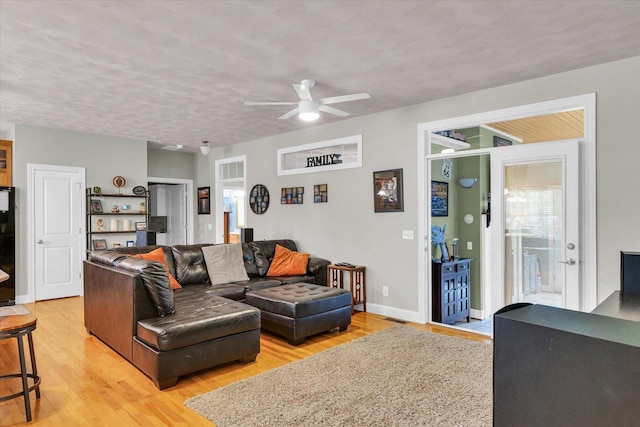 living room with plenty of natural light, a ceiling fan, light wood finished floors, and a textured ceiling