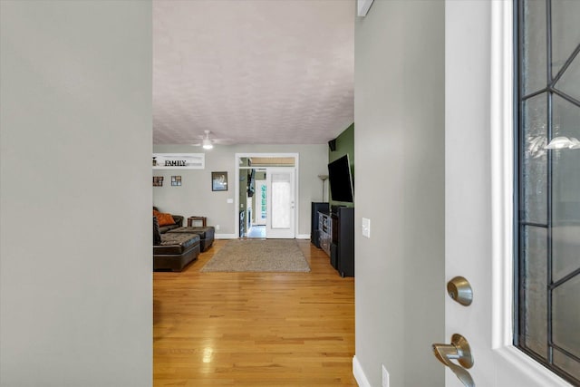 foyer with baseboards, a textured ceiling, ceiling fan, and light wood finished floors