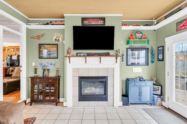 living area with baseboards, tile patterned floors, a tiled fireplace, and ornamental molding