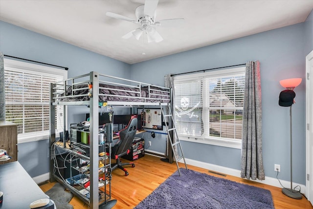 bedroom with visible vents, baseboards, ceiling fan, and wood finished floors