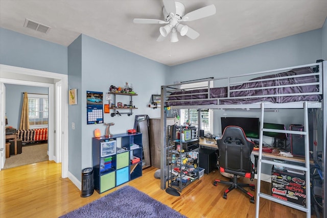bedroom with baseboards, a ceiling fan, wood finished floors, and visible vents