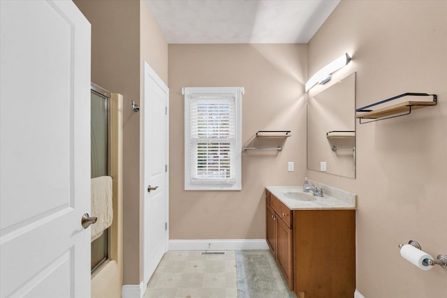 full bathroom with vanity, baseboards, a shower with door, and visible vents