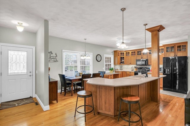 kitchen featuring light countertops, brown cabinetry, black appliances, and light wood-type flooring