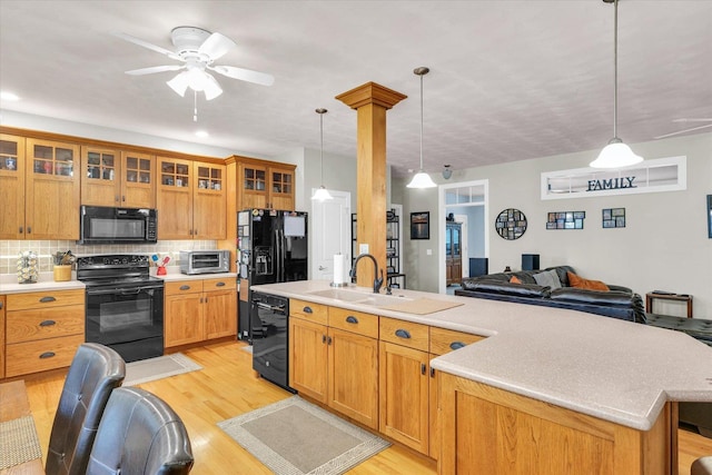 kitchen with a sink, light countertops, black appliances, and light wood-style flooring