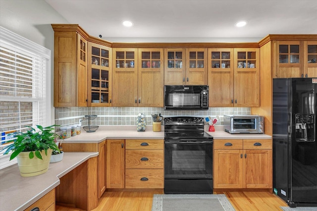 kitchen with light countertops, backsplash, black appliances, and a toaster
