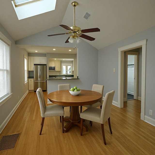 3114 N Long Ave, Chicago, IL 60641 - dining space featuring ceiling fan, visible vents, lofted ceiling with skylight, and light wood-style floors