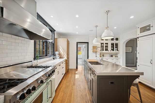 420 Washington Ave, Glencoe, IL 60022 - kitchen featuring stainless steel counters, wall chimney exhaust hood, a sink, arched walkways, and range