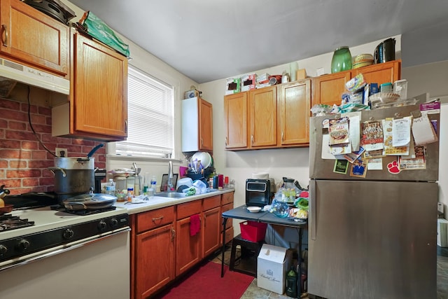 kitchen with light countertops, freestanding refrigerator, decorative backsplash, under cabinet range hood, and white range with gas cooktop