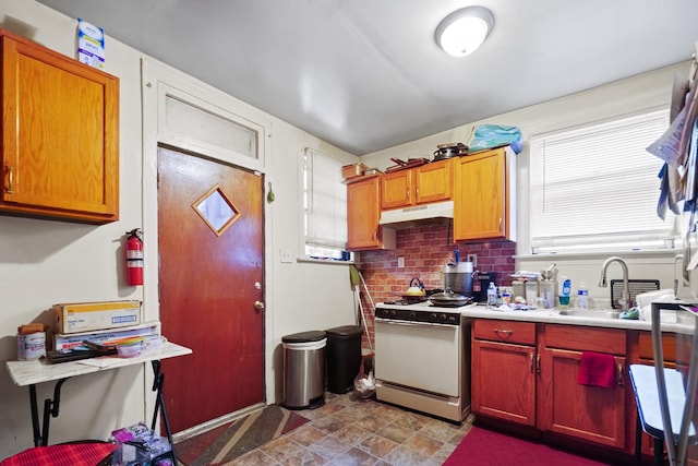kitchen with white range with gas stovetop, light countertops, under cabinet range hood, a sink, and backsplash