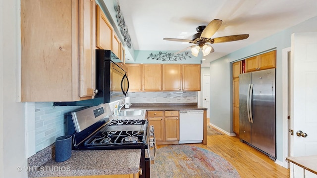 kitchen featuring ceiling fan, a sink, light wood finished floors, stainless steel appliances, and backsplash
