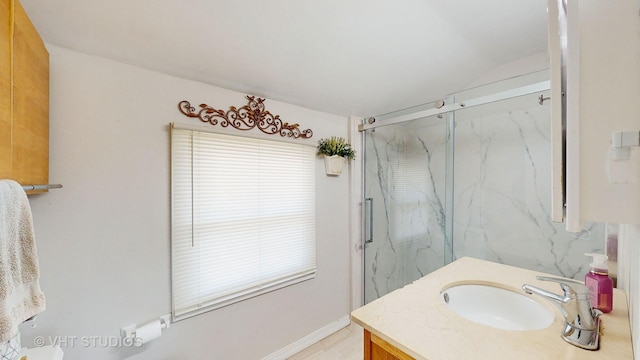 bathroom with vanity, a marble finish shower, baseboards, and vaulted ceiling