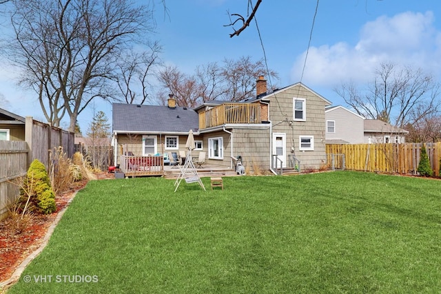 back of house featuring a fenced backyard, a wooden deck, a chimney, and a yard