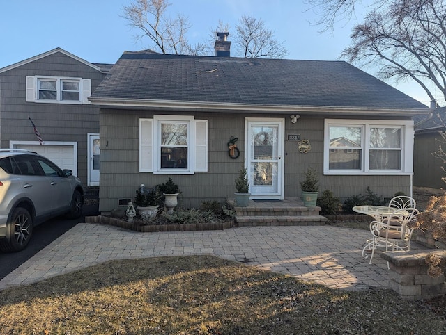 view of front of property featuring a chimney, roof with shingles, and a garage