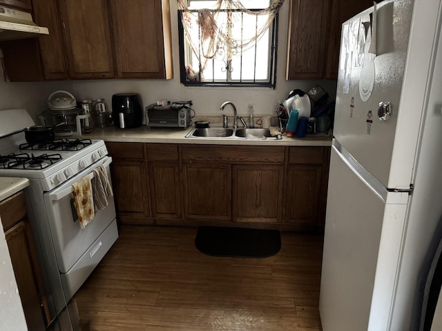 kitchen with a sink, light countertops, under cabinet range hood, and white appliances