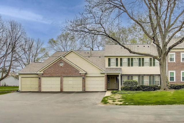 1608 Pennsbury Ct Unit A2, Wheeling, IL 60090 - view of front of home with brick siding, a shingled roof, asphalt driveway, a front lawn, and a garage